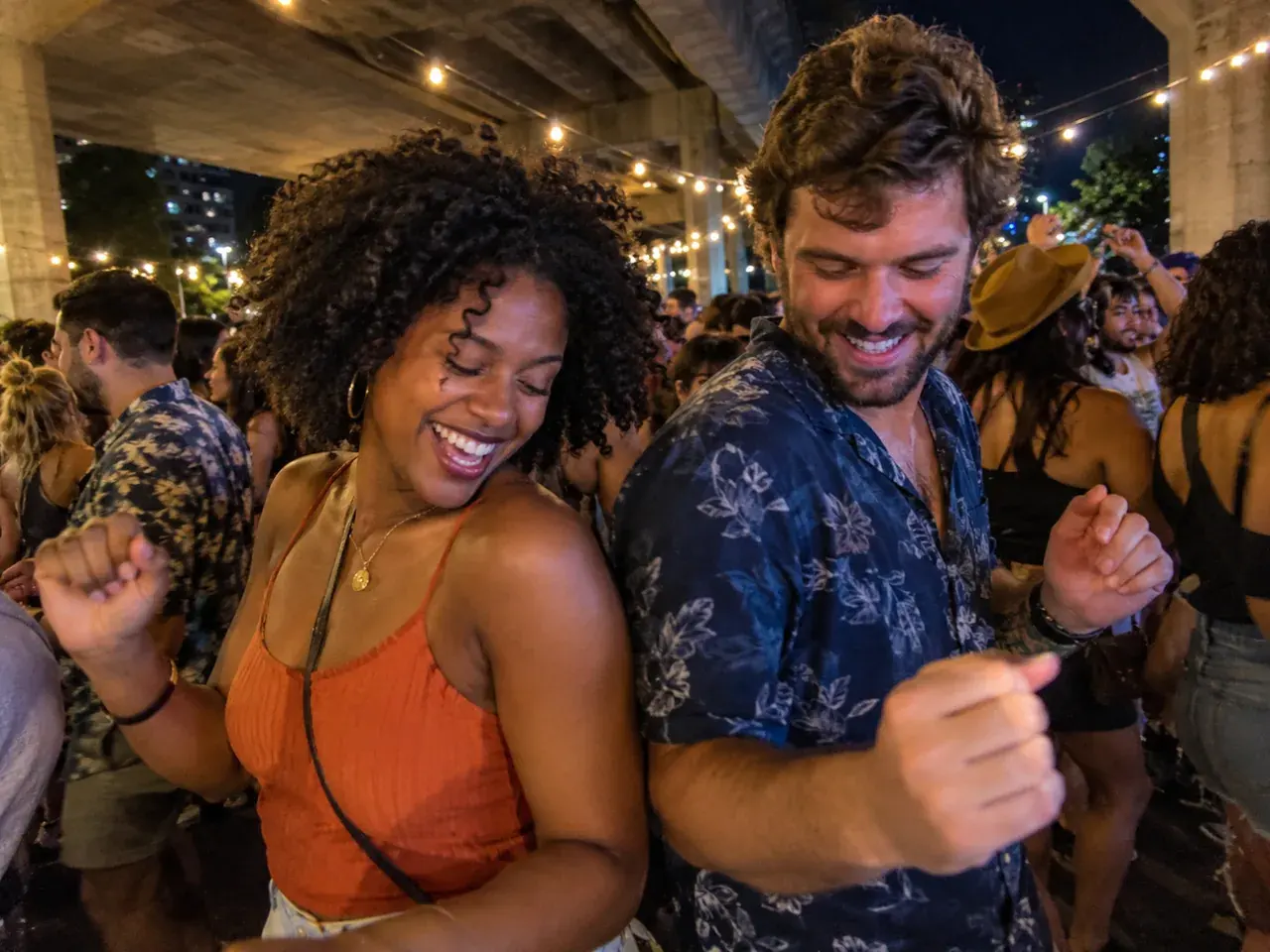 Two adults dancing shoulder to shoulder in a crowded outdoor night dance party