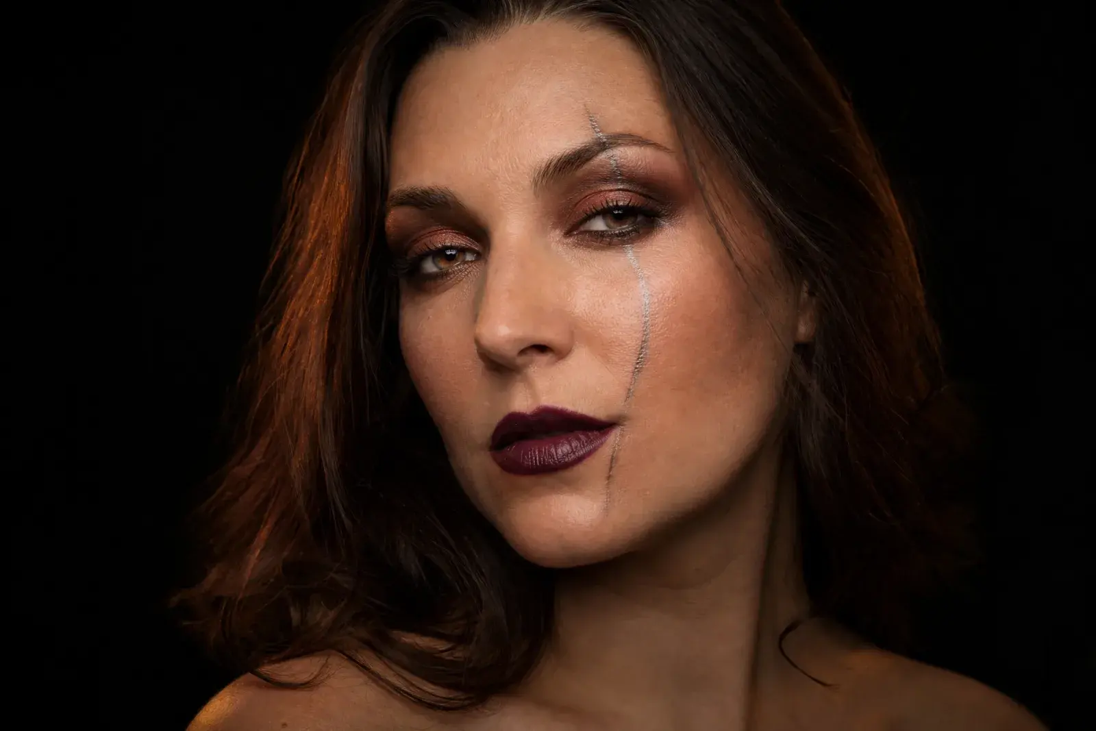Nahaufnahme eines Halloween-Porträts mit kupferfarbenem Augen-Make-up und bernsteinfarbenem Studiolicht